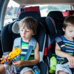 Two boy in car seats, traveling in car and playing