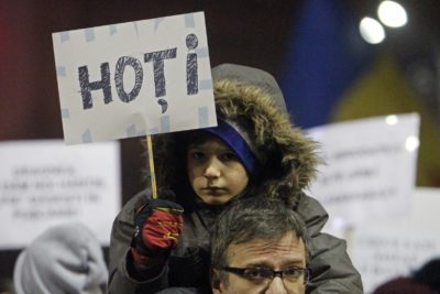 Na proteste so svoji starši vzeli tudi otroke. Tale deček na očetovih ramenih drži napis "Tatovi". Slika je nastala 4.2.2017 ob množičnih protestih v Bukarešti. Foto: epa