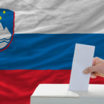 man voting on elections in slovenia front of flag