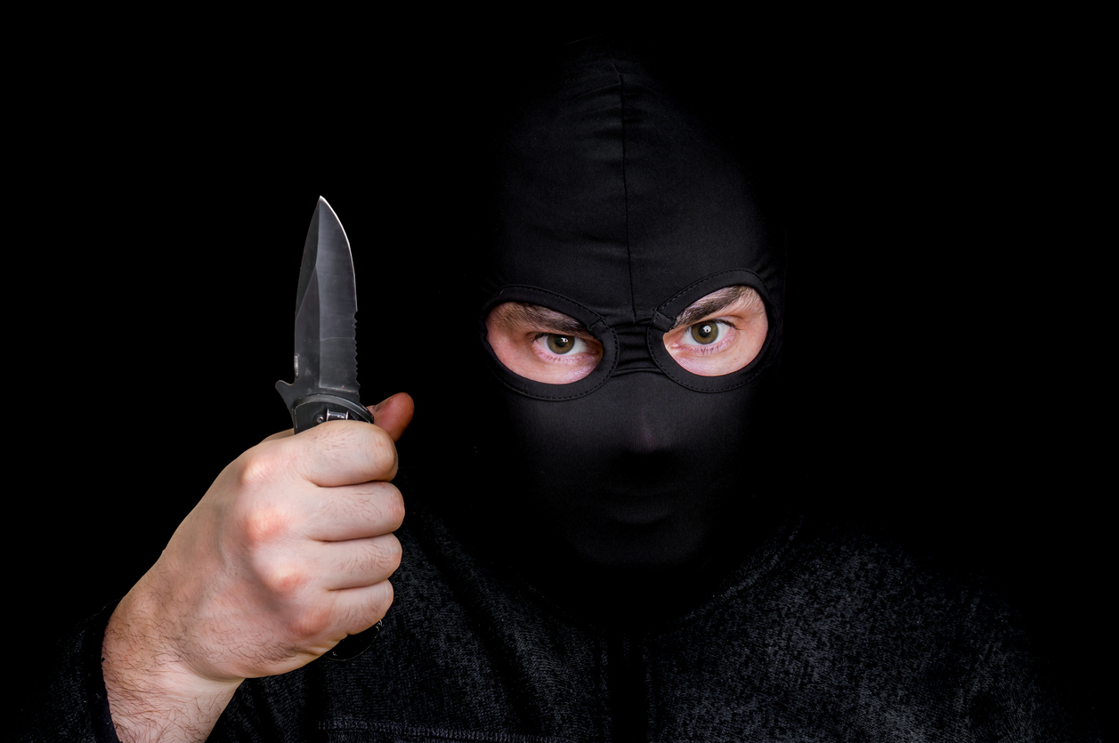 Masked man in balaclava with knife isolated on black Nova24TV