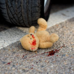 toy bear in the blood under the car wheels