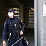 Policistka pred vlado in propagandni plakat