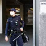 Policistka pred vlado in propagandni plakat