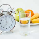 Alarm and glass of water near fruits